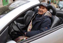 Garbaus amžiaus senolis laisvalaikiu sėda prie kabrioleto vairo